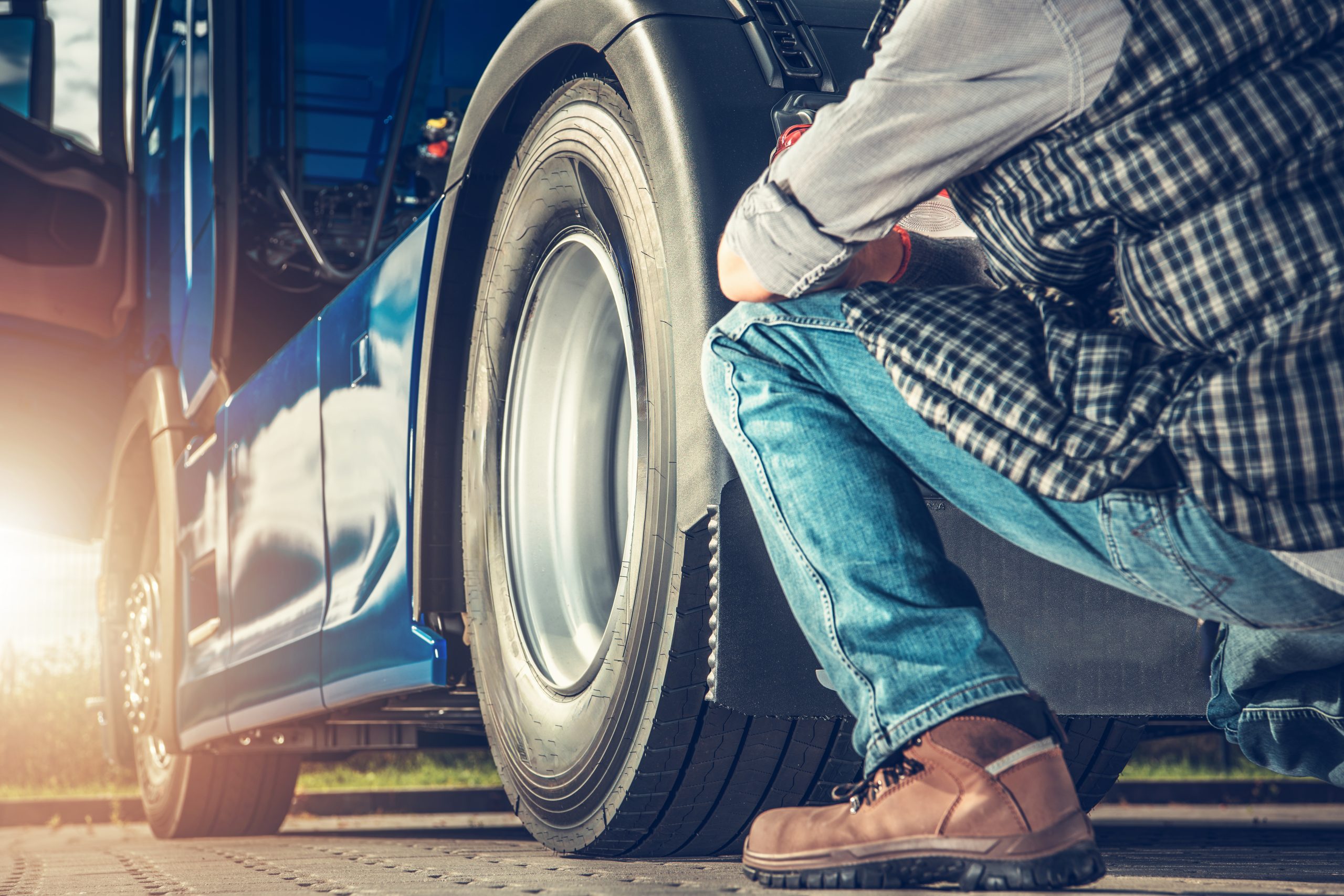 Semi Truck Mechanic Inspecting Vehicle Tire During Daytime Repair in Urban Area